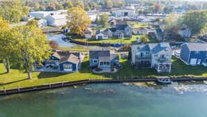 Vista aérea de una zona residencial junto al lago, con casas, un muelle y un barco.