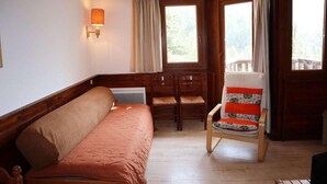 A room with a wooden bed, a wooden chair, a small table, and a window with curtains. - Ski-in/ski-out & foot of the slopes, 2nd floor, balcony, tv, ski locker, 32m², Les Orres (Les Orres)