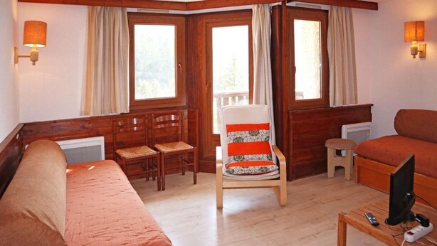 A cozy room with a bed, a chair, a small table with a TV, and a window with curtains. - Ski-in/ski-out & foot of the slopes, 2nd floor, balcony, tv, ski locker, 32m², Les Orres (Les Orres)