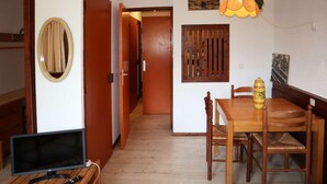 A dining area with a wooden table and chairs, a television on a wooden stand, and a decorative lamp. - Ski-in/ski-out & foot of the slopes, 2nd floor, balcony, tv, ski locker, 32m², Les Orres (Les Orres)