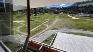 A view from a window overlooking a grassy area with a wooden deck, a dirt path, and a mountain in the background. - Ski-in/ski-out & foot of the slopes, 2nd floor, view ski slopes, balcony, tv, 20m², La Plagne (La Plagne)