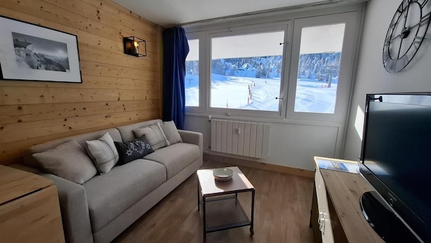 A cozy room with a wooden wall, a sofa, a small table, and a TV. - Ski-in/ski-out & foot of the slopes, 2nd floor, view ski slopes, balcony, tv, 20m², La Plagne (La Plagne)