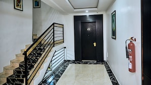 A staircase with black and gold railings, a fire extinguisher mounted on the wall, and a door labeled "FLAT 411". - Executive Luxury Room - Sleeps 2 - Pool - Gym (Lekki)