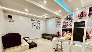 Un moderno salón de spa con un espejo grande, un sofá y una mesa de vidrio.