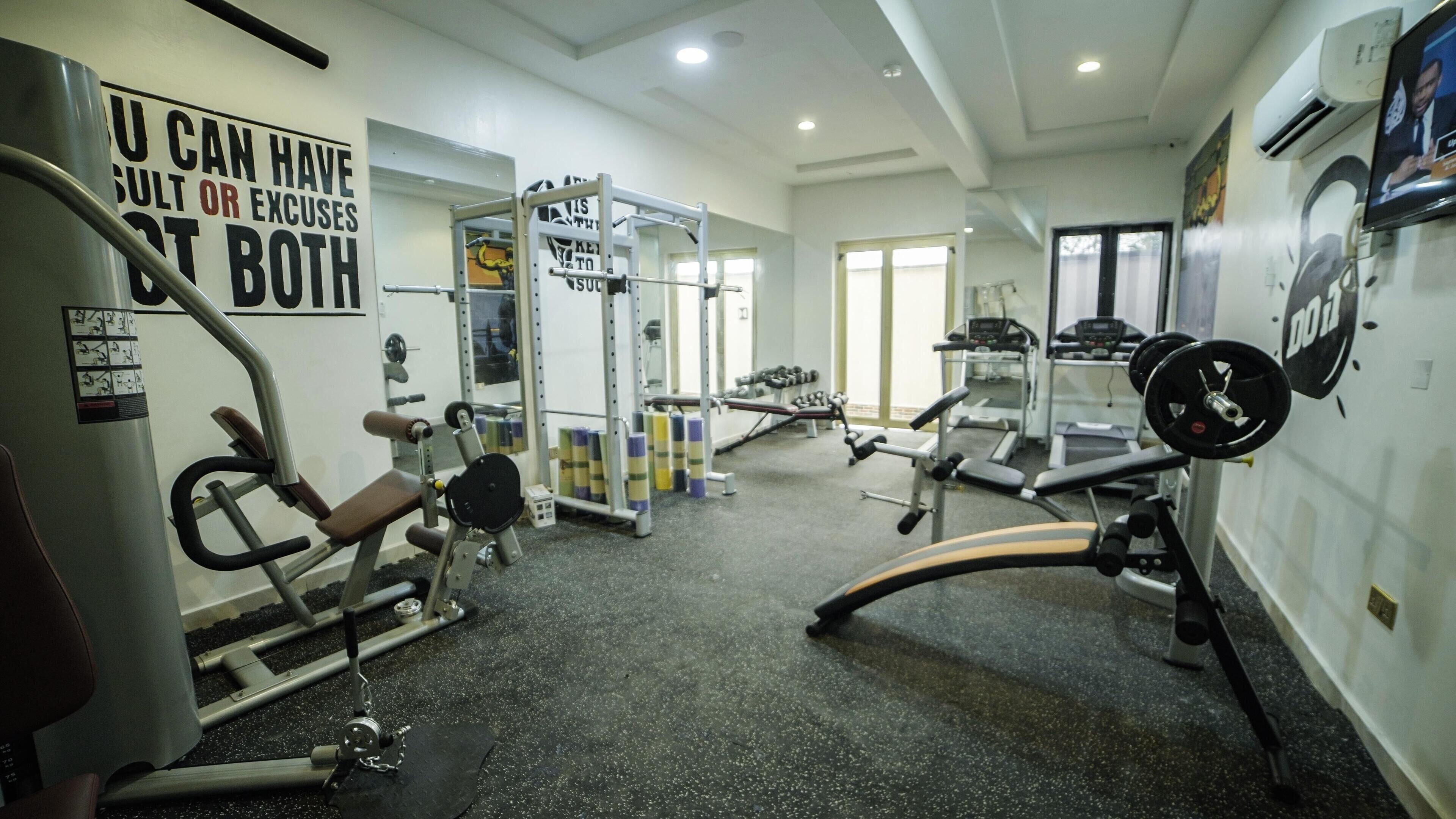 A gym with various exercise equipment, including a bench press, squat rack, and treadmill.
