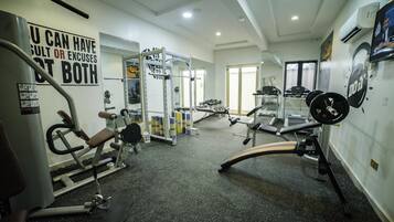 A gym with various exercise equipment, including a bench press, squat rack, and treadmill.