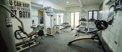 A gym with various exercise equipment, including a bench press, squat rack, and treadmill.