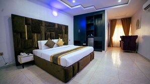 Una habitación de hotel moderna con una cama grande, una mesita de noche, un armario y una zona de estar con una silla.