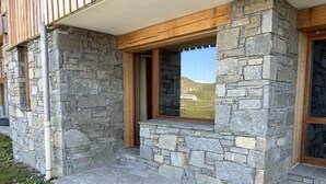 Ein Steinhaus mit einer Holzveranda und einem Fenster mit Bergblick.
