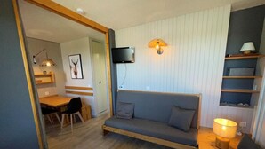 Ein gemütliches Wohnzimmer mit einer Couch, einem Holztisch und einem an der Wand befestigten Fernseher.