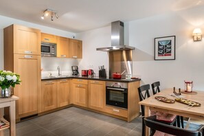 A modern kitchen with wooden cabinets, stainless steel appliances, and a dining area with a table and chairs.