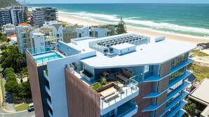 Un hôtel moderne doté d’une piscine sur le toit, de nombreux balcons et offrant une vue sur la plage et l’océan.