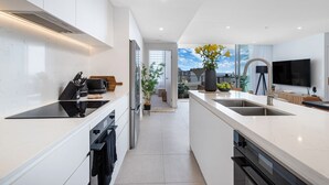 Une cuisine moderne avec des meubles blancs, un îlot central et une cuisinière intégrée.