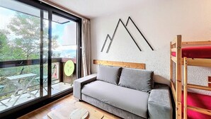 A modern room with a grey sofa, a wooden bunk bed, a large window with a view of trees, and a minimalist wall art piece. - 2nd floor, view mountain, swimming pool, balcony, tv, ski locker, 21m², Le Corbier (Le Corbier)