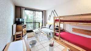 A compact room with a bunk bed, a sofa, a small table, and a TV. - 2nd floor, view mountain, swimming pool, balcony, tv, ski locker, 21m², Le Corbier (Le Corbier)