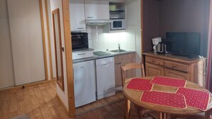 A compact kitchen with a microwave, sink, and a dining area with a table. - 100m from resort center, 3rd floor, balcony, tv, ski locker, 30m², Brides Les Bains (Brides-les-Bains)