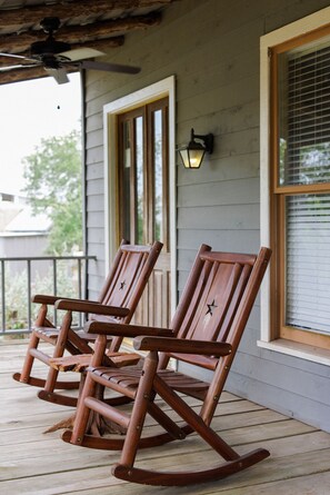 Une véranda avec des fauteuils à bascule en bois et un ventilateur de plafond.
