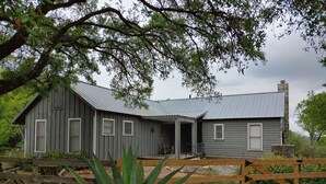 Ein rustikales Holzhaus mit Metallbedachung, umgeben von einem Holzzaun und viel Grün.