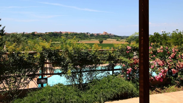 A covered outdoor area with a view of a swimming pool, greenery, and distant buildings. - Farmhouse in Montalto Near Sandy Beaches (Montalto di Castro)