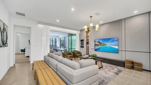 Una sala de estar moderna con un sofá seccional, una mesa de centro y un televisor montado en la pared.