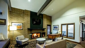 A living room with a fireplace, comfortable seating, and a television mounted on the wall.