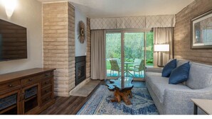 A living room with a fireplace, a sofa, a coffee table, and a view of a patio with outdoor furniture.