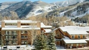 A lodge with a large building and smaller cabins, surrounded by snow-covered mountains.