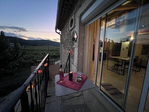 A balcony with a table set for two, a bottle, and glasses. - Gite de ROSE under the stars in GARD (Pont-Saint-Esprit)