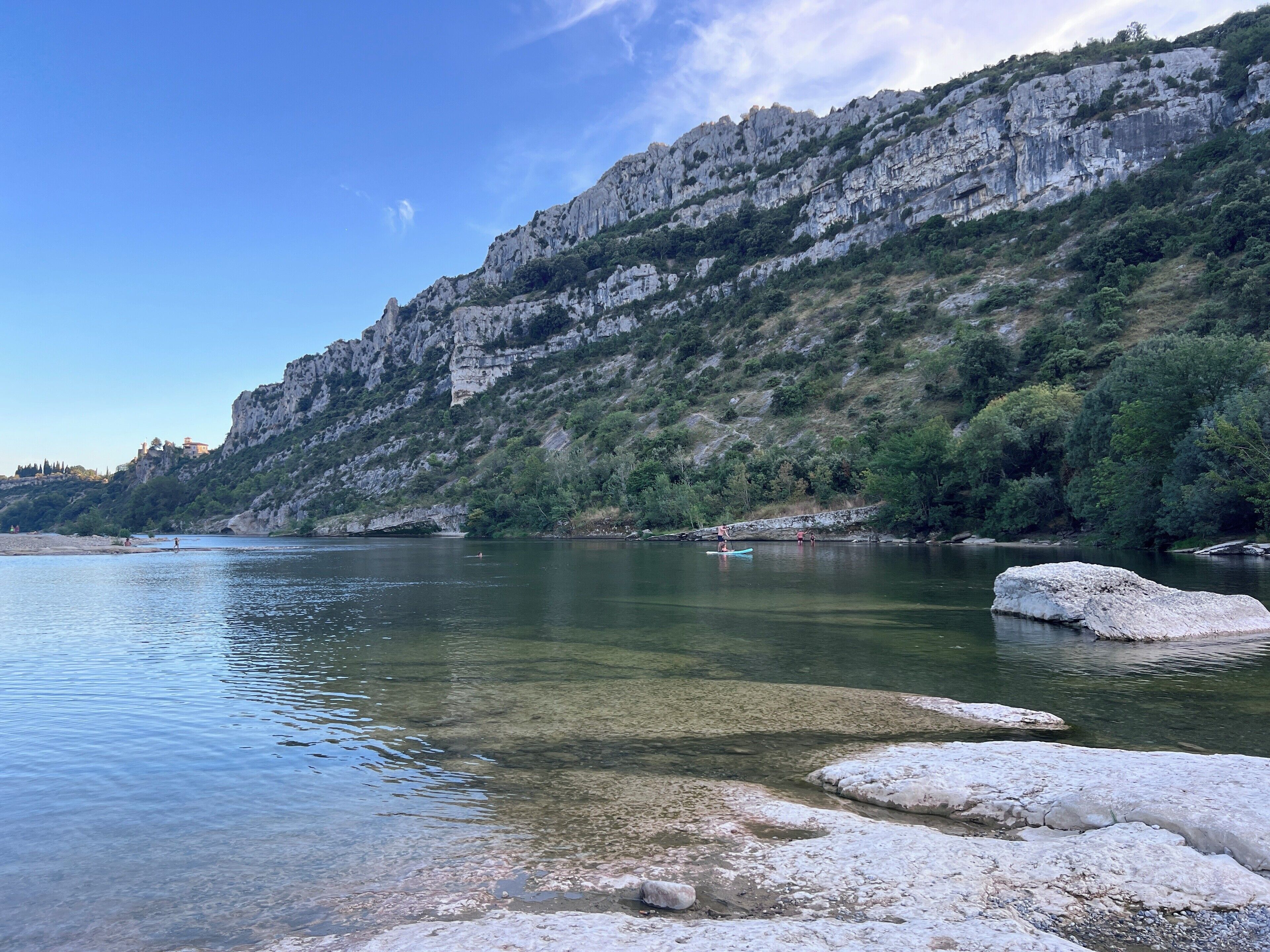 A clear lake with rocky cliffs and sparse vegetation.