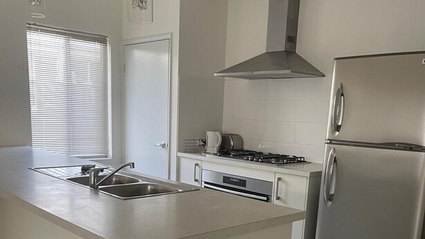 Una cocina moderna con una isla central, electrodomésticos de acero inoxidable y un ventanal con persianas.