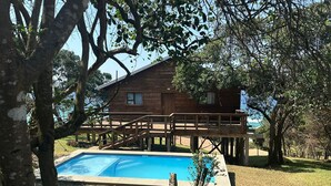 Una cabaña de madera con terraza y piscina.