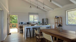 Una cocina amplia con una isla central, taburetes de madera y luminarias colgantes.