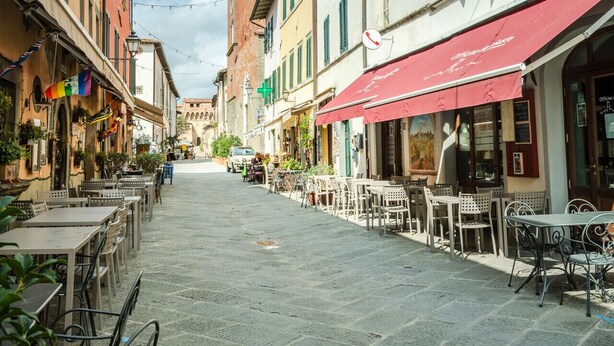 A cobblestone street lined with traditional buildings, a prominent tower, and outdoor seating areas. - Contemporary 2 Bedrooms Apartment in Montecarlo (Montecarlo)
