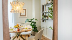 A dining area with a round table set for four, a hanging light fixture, and a shelf with plants. - Contemporary 2 Bedrooms Apartment in Montecarlo (Montecarlo)