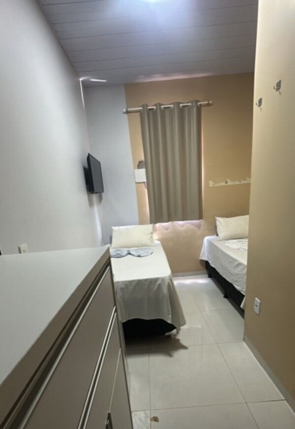 Una stanza piccola e pulita con un letto, una scrivania e una TV montata a parete.