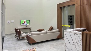A modern hotel lobby with a sofa, chairs, a television, and a reception desk. - Hotel Porto Sollar (Porto Nacional)