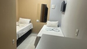 A small hotel room with two beds, a mirror, and a flat-screen TV. - Hotel Porto Sollar (Porto Nacional)