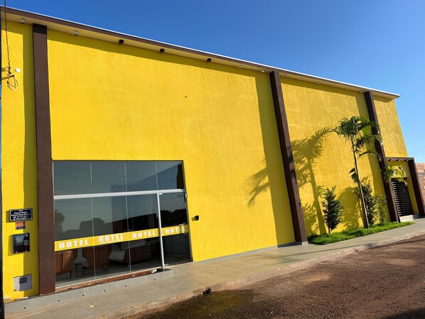 A yellow building with a glass entrance and the words 'HOTEL' repeated on the facade. - Hotel Porto Sollar (Porto Nacional)