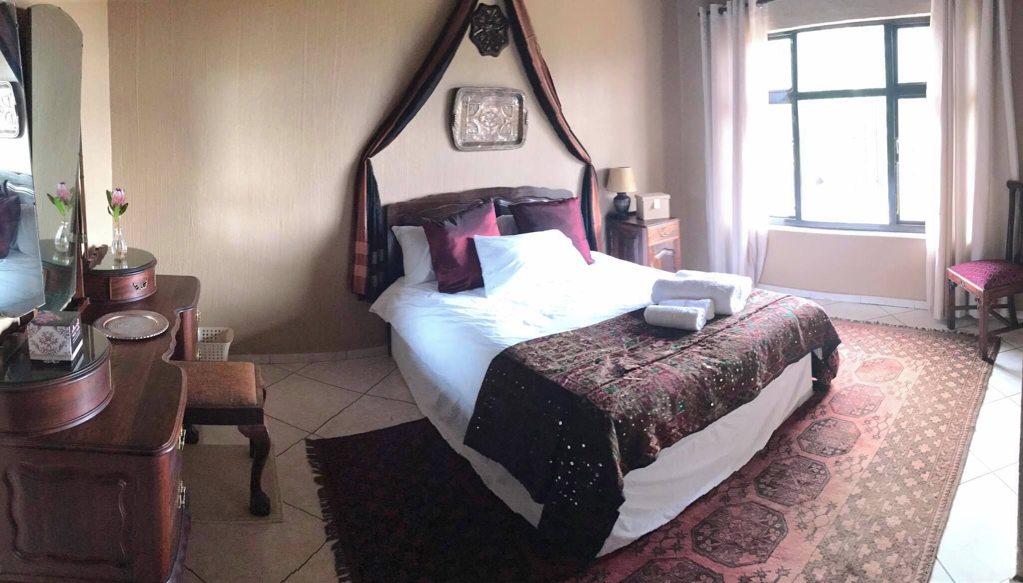 Une chambre d’hôtel comprenant un lit, une table de chevet, une lampe, une chaise, une commode et une fenêtre.