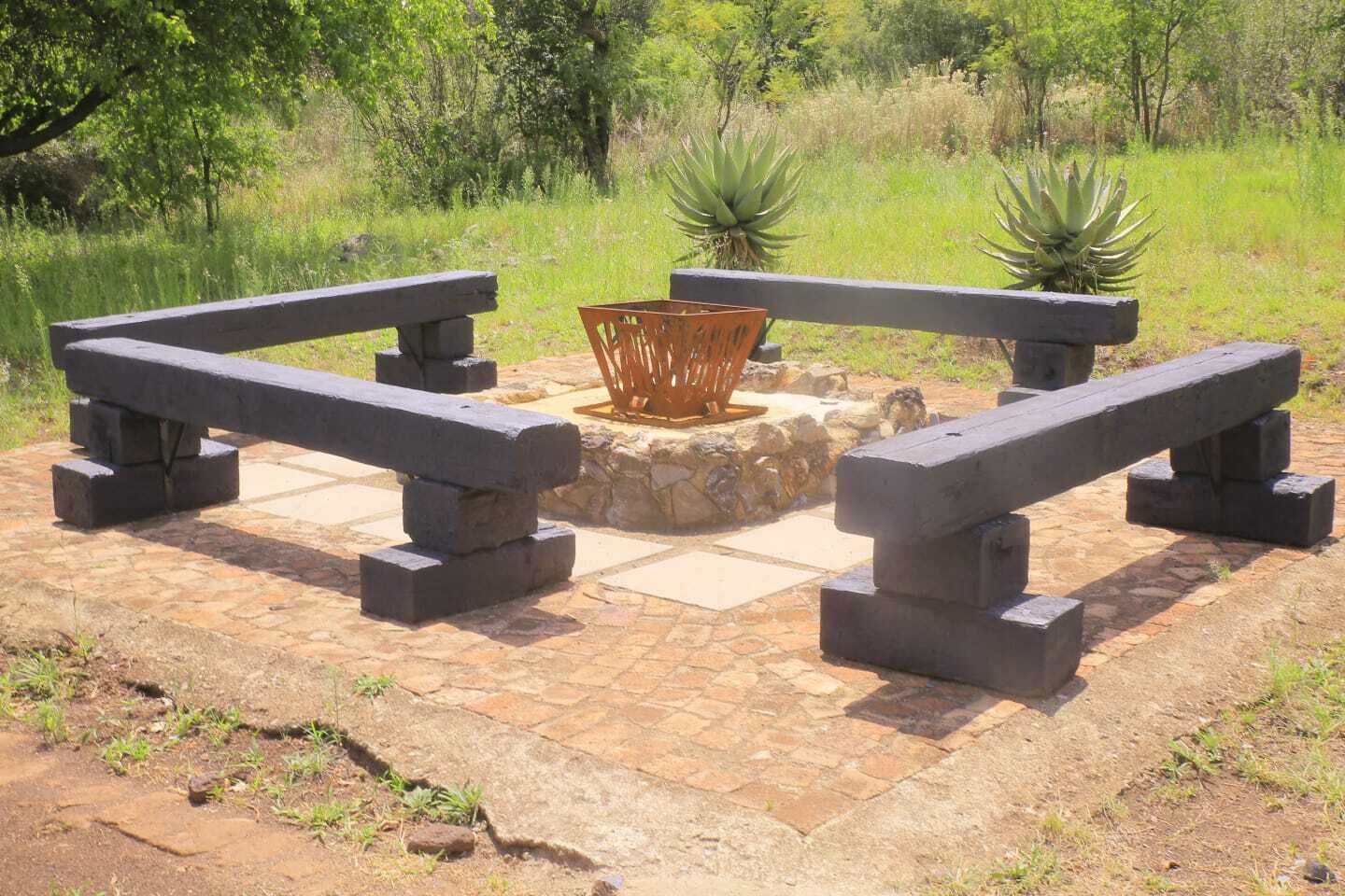 A stone patio with two stone benches and a central fire pit.