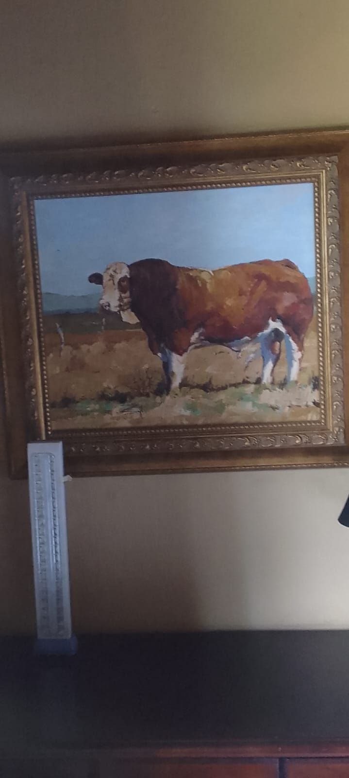 Een lijst met een schilderij van een koe op een boerderij.