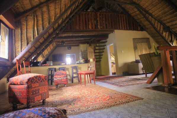 A cozy attic room with a sloped ceiling, a dining area with a table and chairs, and a kitchen area with a counter and stools.