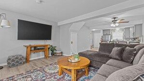 En moderne stue med en grå sofa, et træ sofabord og et tæppe med et mønster.