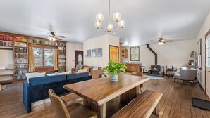 Ein geräumiges Wohnzimmer mit einem Holzesstisch, einem blauen Sofa und einem Bücherregal voller Bücher.