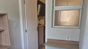 A compact kitchen with a refrigerator, a wooden countertop, and a window above a stool.