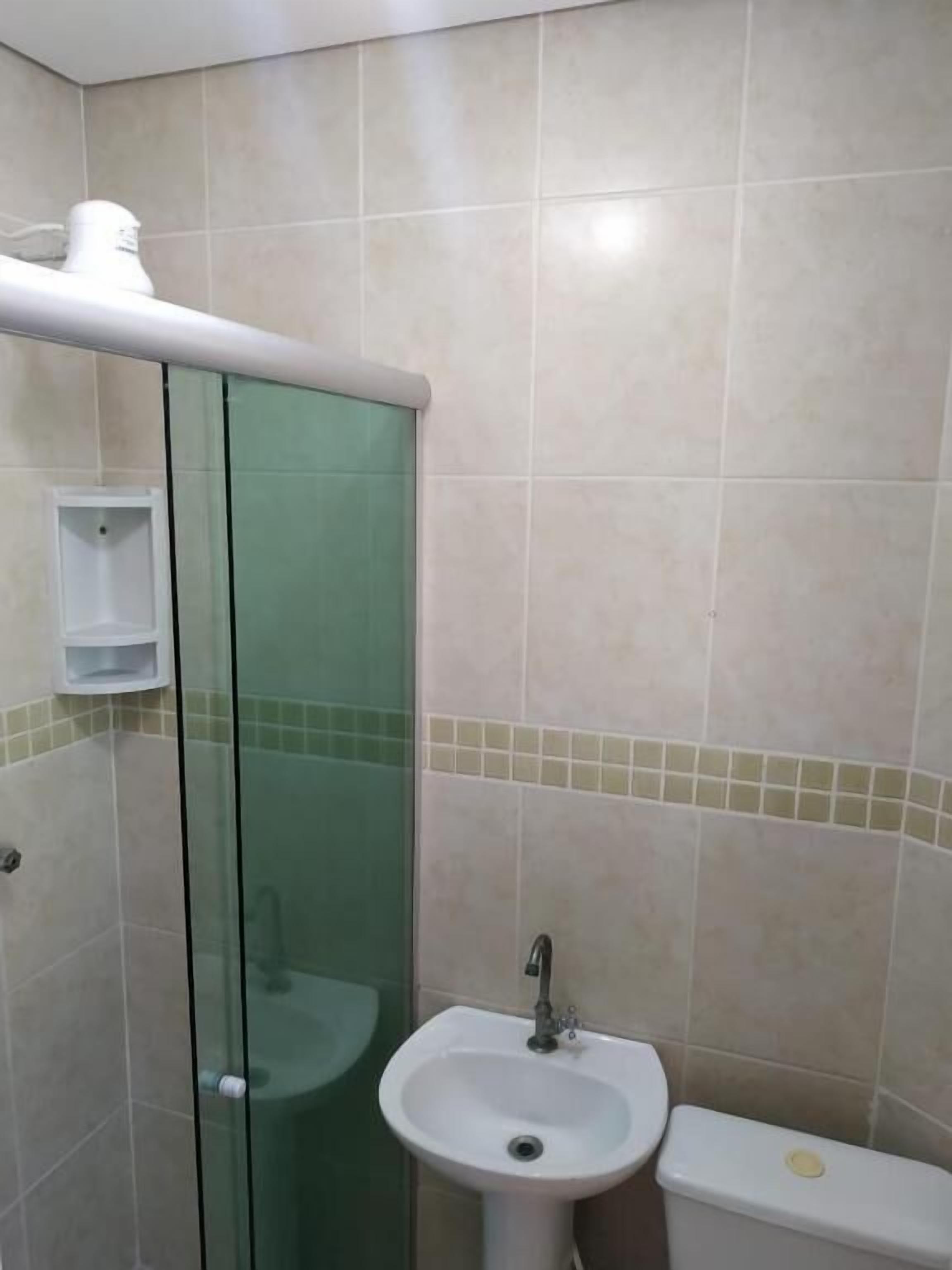 A bathroom with a glass shower enclosure, a white sink, and a toilet.