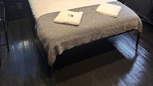 A modern bedroom with a bed, a nightstand, a lamp, and a window with a view of the outside. - Digz Hotel (Middlesbrough)