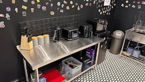 A kitchen with a stainless steel countertop, various appliances, and a black and white tiled floor. - Digz Hotel (Middlesbrough)