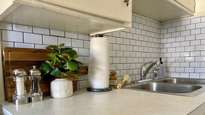 Una cocina con azulejos blancos tipo metro, un lavamanos de acero inoxidable y una encimera de madera.