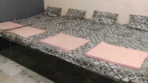 A room with a bed, a ceiling fan, and an air conditioning unit. - HOLKAR SEVA SADAN (Mathura)